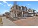 Inviting two-story home featuring stone detailing, a brick driveway, a covered front porch, and mature landscaping at 26167 E Byers Pl, Aurora, CO 80018