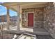 Charming front porch featuring stone accents, a red front door, a covered entrance, and metal railings at 26167 E Byers Pl, Aurora, CO 80018
