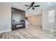 Modern living room with a sleek fireplace, light wood floors, and a ceiling fan at 2443 W 69Th Pl, Denver, CO 80221