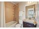 Bathroom featuring a tub/shower combo with tiled walls, granite vanity, and mirrored cabinet at 2562 S Kendrick St, Denver, CO 80228