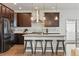 Gourmet kitchen featuring a stainless steel fridge and exhaust hood, dark cabinets, and bar stool seating at 2562 S Kendrick St, Denver, CO 80228