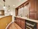 Elegant home bar with rich wood cabinetry, mosaic tile backsplash, and beverage fridge at 2571 Hunters Pl, Highlands Ranch, CO 80129