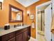 Inviting bathroom with orange walls, a framed mirror, and a tiled shower stall at 2571 Hunters Pl, Highlands Ranch, CO 80129