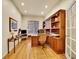 Well-lit home office featuring wood floors, built-in shelves, and a large desk at 2571 Hunters Pl, Highlands Ranch, CO 80129