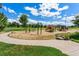 Scenic playground in a lush, green park with mature trees, benches, and various play structures at 7000 E Quincy Ave # 204, Denver, CO 80237