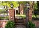 Beautiful brick home featuring a secure iron gate with brick pillars and manicured shrubs at 100 N Gaylord St, Denver, CO 80206