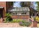 Close-up of greenhouse with brick base and glass roof surrounded by greenery and flowers at 100 N Gaylord St, Denver, CO 80206