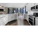 Open kitchen and dining area with sleek white cabinets, stainless steel appliances, and wood flooring at 1734 Summerglow Ln, Monument, CO 80132
