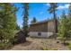 Back exterior of a two story home with a wood shed and trees surrounding the property at 24 Ski Pole Ct, Breckenridge, CO 80424