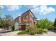 Exterior view of townhomes showcasing brick architecture, a covered deck, and green landscaping at 2933 Central Park Blvd, Denver, CO 80238