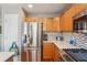 Open kitchen featuring stainless steel refrigerator, wooden cabinets, granite countertops, and stainless steel appliances at 2933 Central Park Blvd, Denver, CO 80238