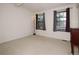 Bright bedroom with neutral carpet, two windows with curtains, and a standing lamp at 8144 Washington St # 192, Denver, CO 80229