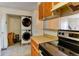 Practical kitchen layout with stacked washer/dryer, light countertops, and overhead cabinetry at 8144 Washington St # 192, Denver, CO 80229