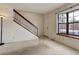 Bright living room featuring large windows, neutral carpet, and staircase with dark railing at 8144 Washington St # 192, Denver, CO 80229