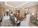 Spacious dining room features a long wooden table, ten chairs, elegant chandelier and patterned wallpaper at 5335 E 2Nd Ave, Denver, CO 80220