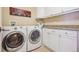Well-organized laundry room features modern washer and dryer units, white cabinets, and neutral countertops at 5335 E 2Nd Ave, Denver, CO 80220