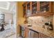 Charming wet bar with granite countertop, wine fridge, backsplash, and glass-front cabinets at 5335 E 2Nd Ave, Denver, CO 80220