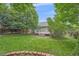 Well-maintained backyard with mature trees, lush lawn, a brick garden border, and a partial view of the deck at 9406 Troon Village Way, Lone Tree, CO 80124