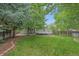 Beautifully landscaped backyard featuring a green lawn, mature trees, a deck, and a brick-lined garden bed at 9406 Troon Village Way, Lone Tree, CO 80124