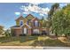 Charming two-story brick home featuring a well-manicured lawn and mature trees on a sunny day at 3163 Soaring Eagle Ln, Castle Rock, CO 80109