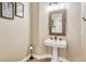 Stylish powder room with a pedestal sink, decorative mirror, and wood-look flooring at 3163 Soaring Eagle Ln, Castle Rock, CO 80109