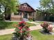 Charming brick home featuring a cozy front porch and a well-manicured lawn with vibrant rose bushes at 1418 Perry St, Denver, CO 80204