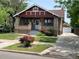 Charming brick home featuring a cozy front porch and a well-manicured lawn with vibrant rose bushes and driveway at 1418 Perry St, Denver, CO 80204