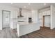 Modern kitchen with white cabinets, stainless steel appliances, quartz counters and wood-look floors at 8672 Pennycress Dr, Littleton, CO 80125