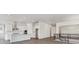 Open-concept living area with modern kitchen with white cabinets, stainless steel appliances and wood-look flooring at 8672 Pennycress Dr, Littleton, CO 80125