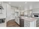 Open kitchen featuring white cabinets, a large island, quartz countertop and stainless steel appliances at 8672 Pennycress Dr, Littleton, CO 80125