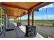 Inviting covered patio with wood ceiling, stone pillars, and serene outdoor views of the surrounding landscape at 3308 County Road 19, Fort Lupton, CO 80621