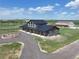 Stunning exterior shot of gray farmhouse, showcasing circular driveway, covered porch, and adjacent multi-bay garage at 3308 County Road 19, Fort Lupton, CO 80621