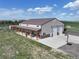 Aerial view of the large metal shop, showcasing covered porch, multi-bay garage doors, and concrete parking pad at 3308 County Road 19, Fort Lupton, CO 80621