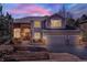 Charming two-story home showcasing brick and siding details under a twilight sky with illuminated interior at 7271 Brixham Cir, Castle Pines, CO 80108
