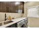 Laundry room with a sink and modern washer and dryer with dark wood cabinets and countertops at 7271 Brixham Cir, Castle Pines, CO 80108