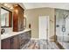 Well-lit main bathroom with double vanity, wood cabinets, and a walk-in shower with glass enclosure at 7271 Brixham Cir, Castle Pines, CO 80108