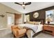 Cozy main bedroom with dark walls, a ceiling fan, barn door entrance to bath, and comfortable seating at 7271 Brixham Cir, Castle Pines, CO 80108