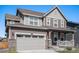 Two-story house with gray siding, a large garage, and a front porch at 10983 Memphis St, Commerce City, CO 80022