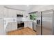 Well-lit kitchen with stainless steel appliances, white cabinetry, and hardwood floors at 6075 S Filbert Ct, Centennial, CO 80121