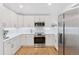 Bright and modern kitchen featuring white cabinets, stainless steel appliances, and ample countertop space at 6075 S Filbert Ct, Centennial, CO 80121