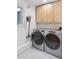 Modern laundry room with light wood cabinets, gray washer/dryer, and stylish patterned flooring at 6075 S Filbert Ct, Centennial, CO 80121