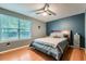 Cozy bedroom with a large window, ceiling fan, wood floors, and an inviting blue color scheme at 12060 N Holly Way, Brighton, CO 80602