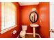 Cozy half-bathroom with red walls, a pedestal sink, and a window with blinds at 20305 E 41St Ave, Denver, CO 80249