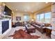Cozy living room with a stone fireplace, leather furniture, large windows, and a cowhide rug at 5195 Raintree Cir, Parker, CO 80134