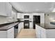 Well-lit kitchen featuring white cabinets, black appliances, granite counters, and a breakfast bar at 7360 E Princeton Ave, Denver, CO 80237