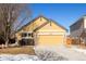 Exterior view of yellow home showcasing attached garage and driveway in front, with stone accents at 16102 Grebe Pl, Parker, CO 80134