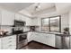 Well-lit kitchen featuring white cabinetry, stainless steel appliances, and dark countertops at 9400 E Iliff Ave # 103, Denver, CO 80231