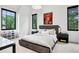 Well-lit bedroom with neutral tones, three windows, two bedside tables, and wall art with a sports jersey at 27 Polo Club Cir, Denver, CO 80209