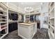 Spacious walk-in closet featuring custom shelving, hanging rods, an island with drawers, and a decorative chandelier at 27 Polo Club Cir, Denver, CO 80209