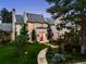 Stunning two-story white brick home featuring a tiled roof and lush, professionally landscaped front yard at 27 Polo Club Cir, Denver, CO 80209